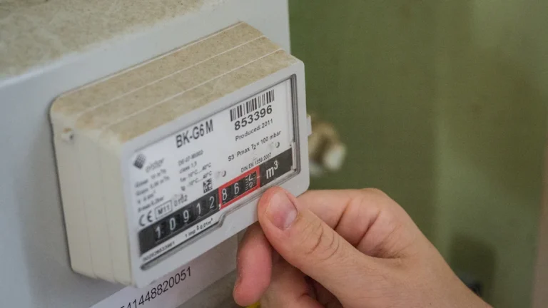 A person's hand checking a residential gas meter for energy usage monitoring.