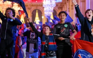 Excited young fans in football jerseys wave blue and red flags in a grand, lit ballroom.