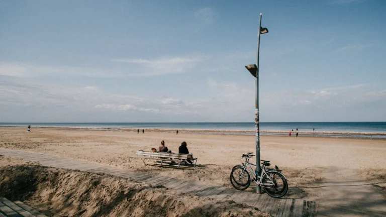 People sitting on a bench at a wide sandy beach in Jurmala near Riga, Latvia.