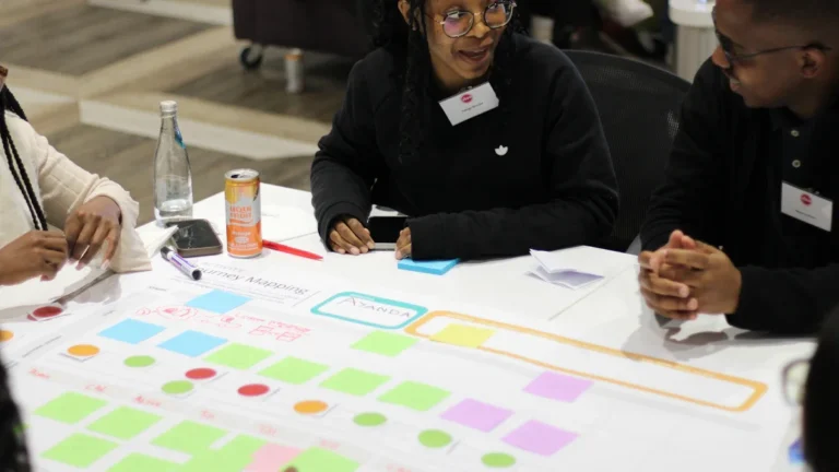 A diverse group of community members collaborating on a planning board with colorful sticky notes and diagrams.