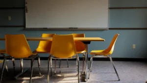 A classroom featuring a large whiteboard and yellow chairs arranged around a table for a meeting.