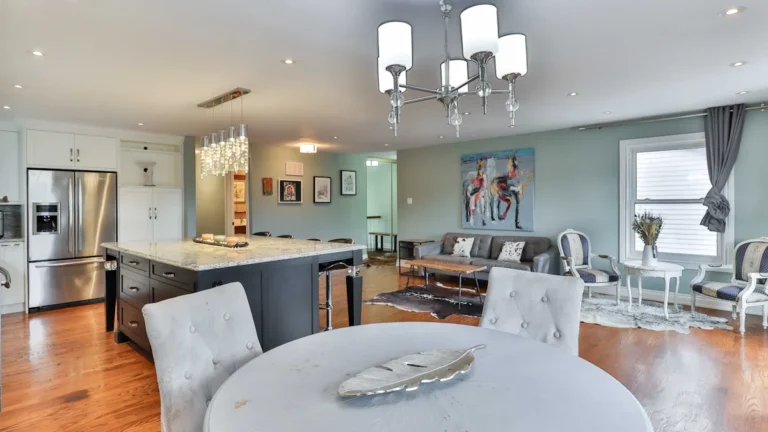 A bright, modern open-plan kitchen and dining area featuring a central island and marble countertops.