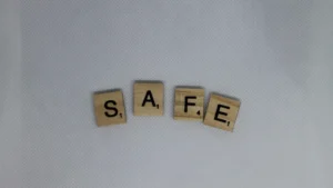 Wooden letter tiles spelling out the word SAFE on a clean white textured background.