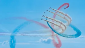 The RAF Red Arrows performing acrobatic loops with vibrant red, white, and blue smoke trails.