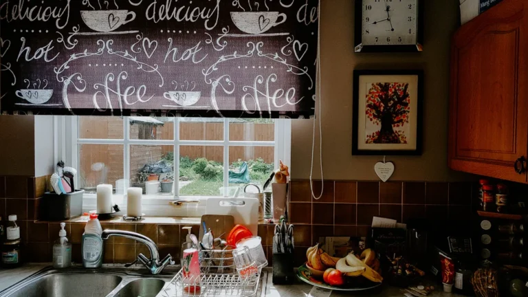 A domestic kitchen sink area in a British home with a window overlooking a garden.