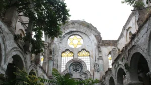 The ruined interior of a synagogue with a Star of David stained glass window visible through the debris.
