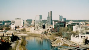 A wide-angle view of the modern Vilnius skyline and Neris River under a clear blue sky.