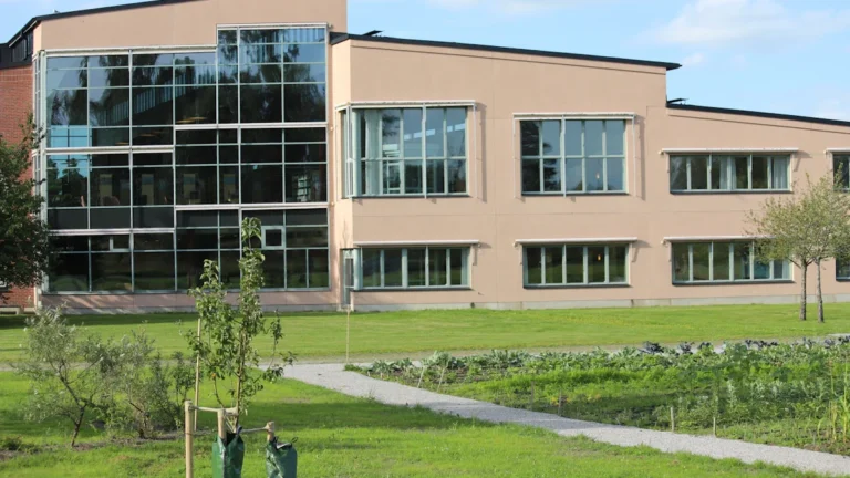 A modern multi-storey building with large glass windows under a clear blue sky.