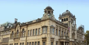 Historic stone building with dome towers and a Union Jack flag flying from the balcony.