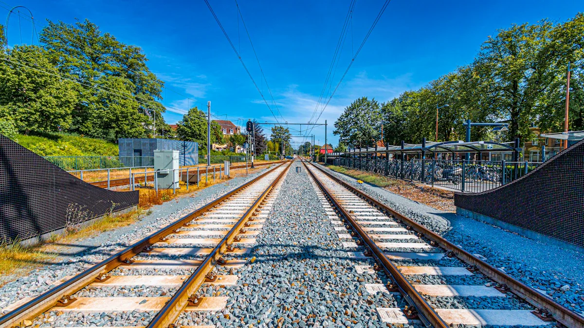 Empty railway tracks stretching into the distance under a clear blue sky.