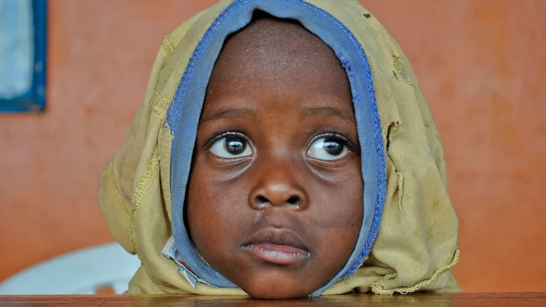Close-up portrait of a young child looking thoughtfully into the distance during a community event.