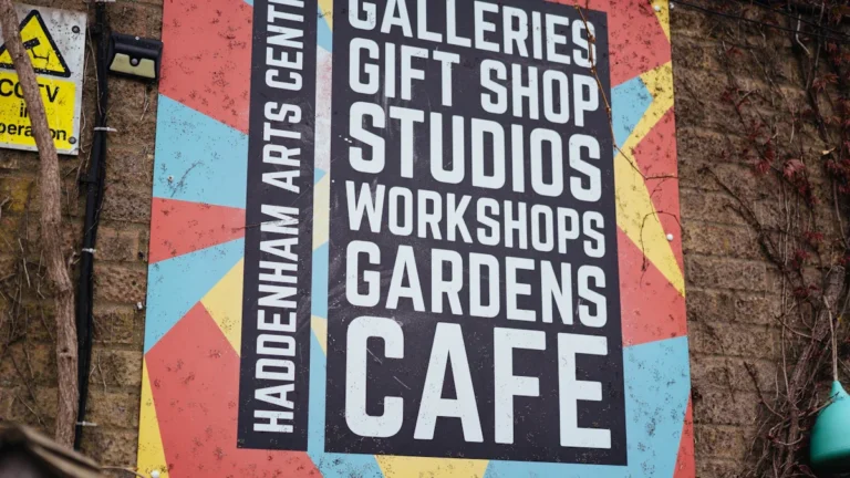 A colorful sign for a UK arts centre listing galleries, studios, workshops, and community spaces.