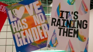 Vibrant Pride posters with inclusive messages displayed on a grid at a creative event in London.