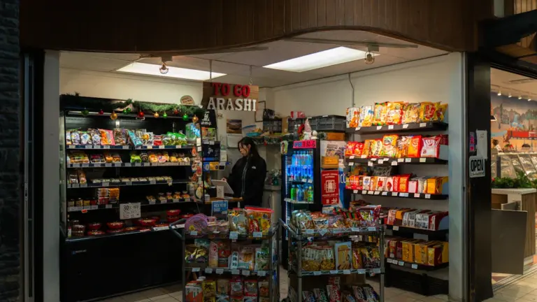 A small convenience store interior with shelves stocked with various snacks and drinks.