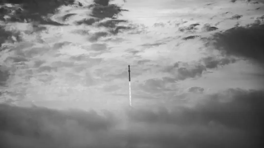 A dramatic black and white shot of a SpaceX rocket ascending into the clouds.