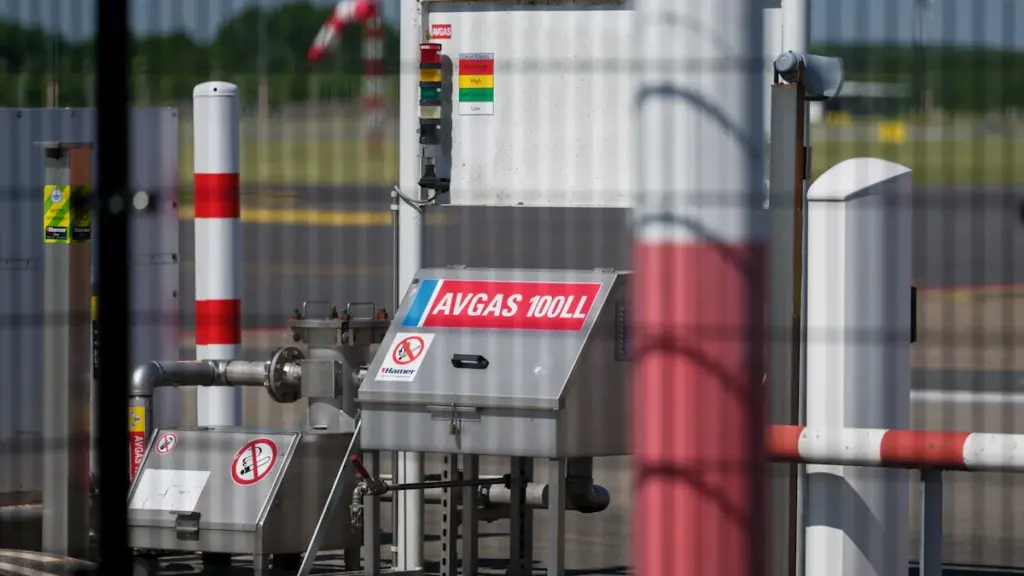 Aviation fuel pump station secured behind a fence at an active airport tarmac.