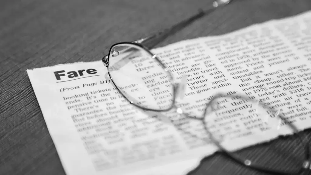 Black framed eyeglasses resting on a printed newspaper with visible text and headlines.