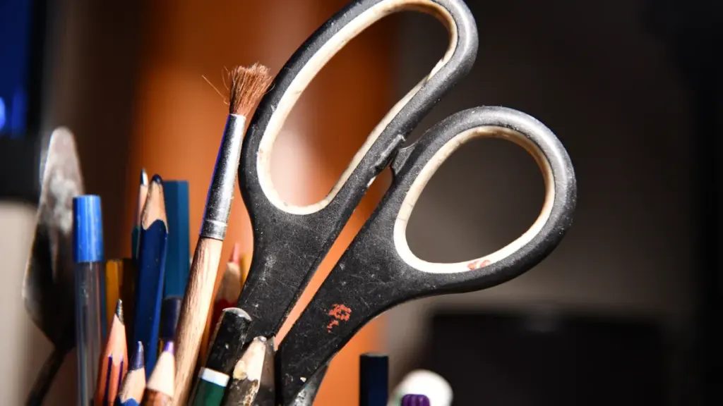 Close up of scissors and various pencils in a desk pencil holder