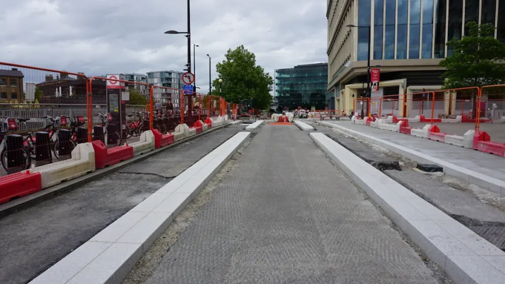 Construction site with safety barriers and gravel pathways at a rail station.