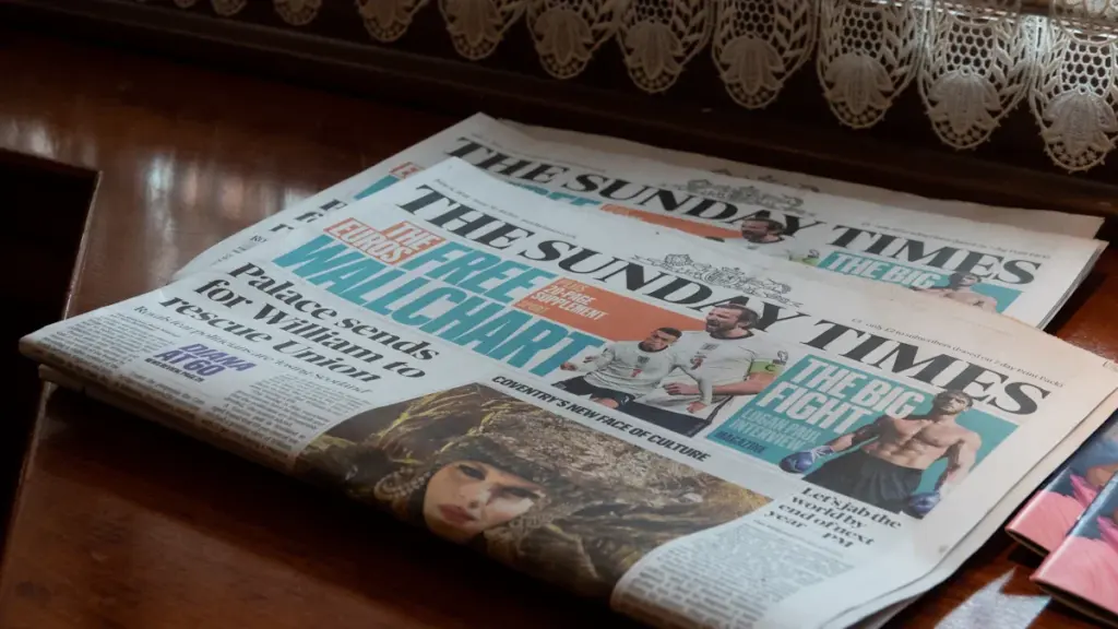 A selection of UK Sunday newspapers laid out on a polished wooden table.