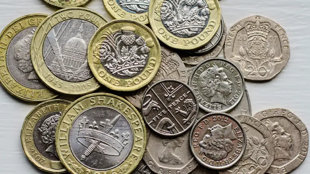 A close-up pile of British sterling coins on a light surface.