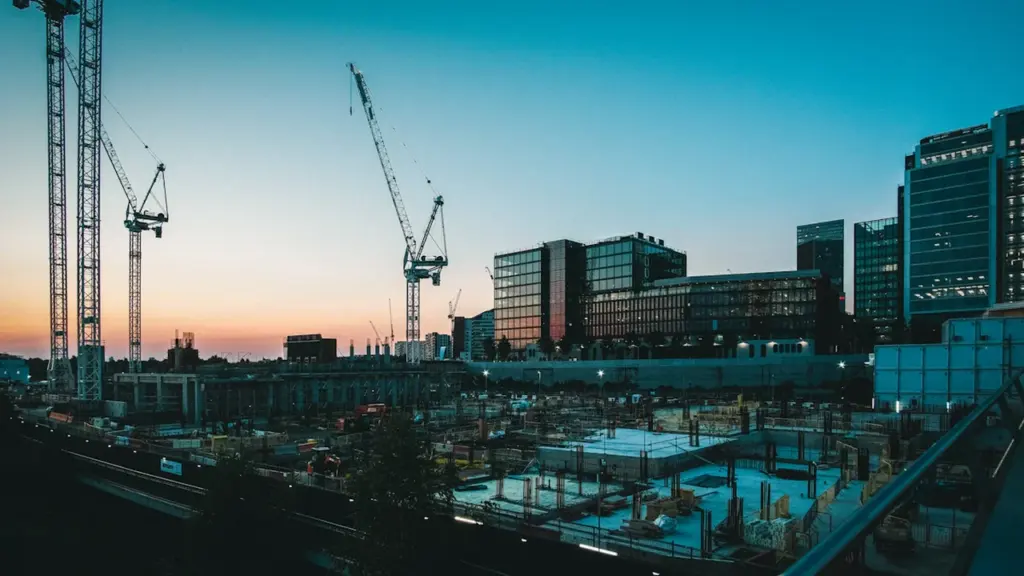 Construction site with tower cranes at dusk in a London urban landscape.