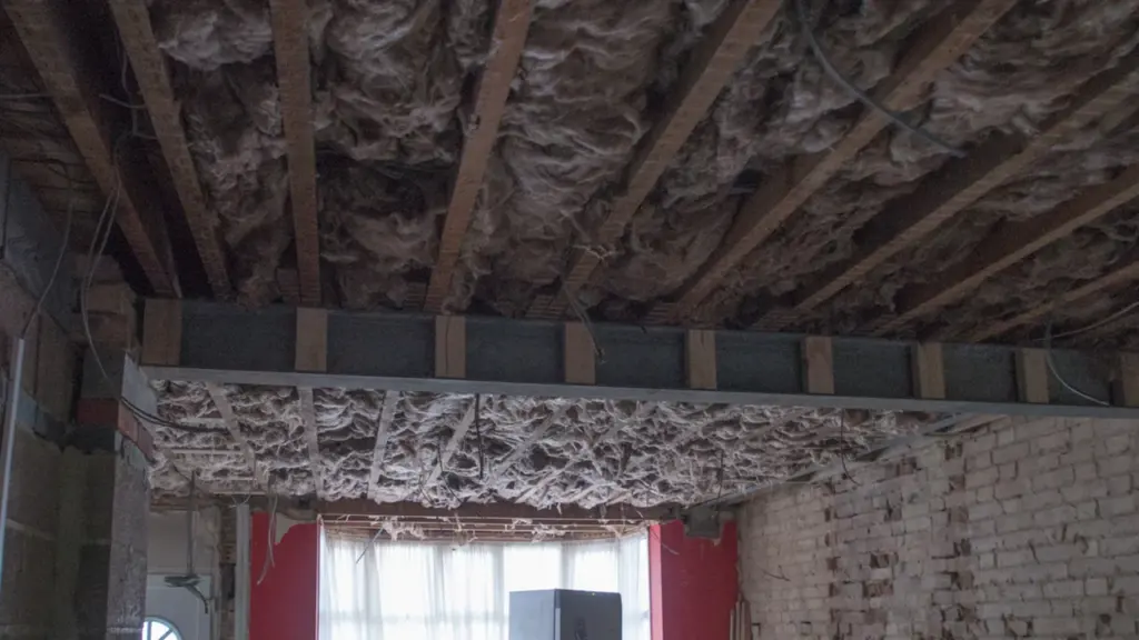 Interior view of a home renovation project featuring exposed ceiling insulation and beams.