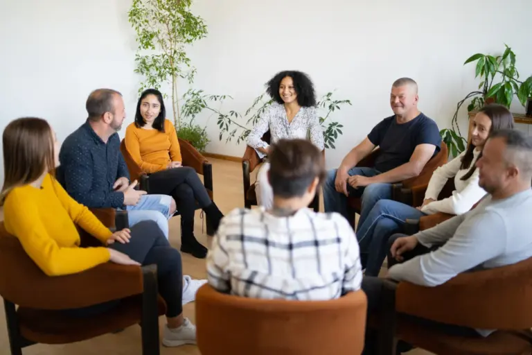 A diverse group of adults sitting in a circle during a support group meeting.