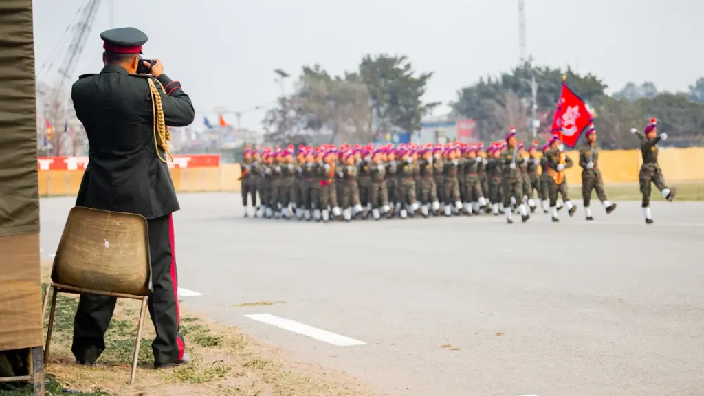A soldier in uniform photographs a formal military parade on a large field.